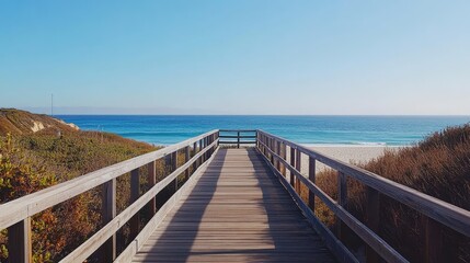Fototapeta premium A wooden boardwalk leading to a coastal building, with the ocean stretching out in the background.