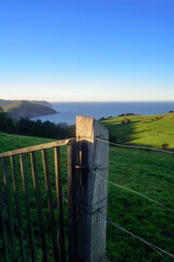 Piquete de madera y puerta de metal en finca de pasto junto al mar en Asturias