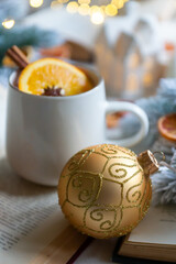 New Year 2025, tea with orange, coffee with marshmallows, books and fir branches, New Year's toys and a ball on the table.