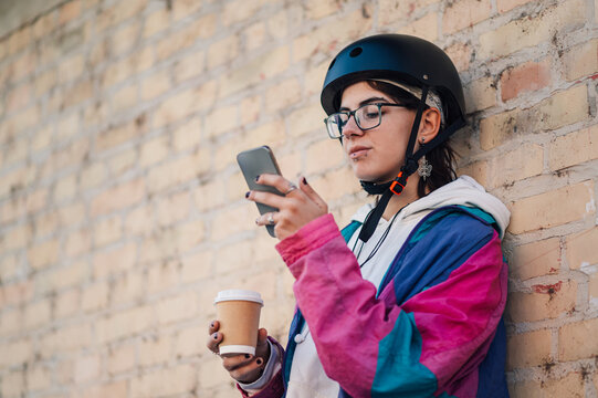 Young urban commuter using smartphone and drinking coffee