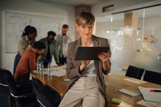 Businesswoman using digital tablet while coworkers are discussing in the background