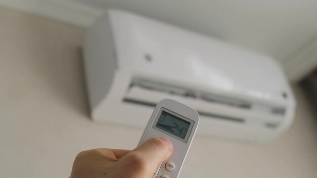 Man turns on air conditioner with remote control, close-up