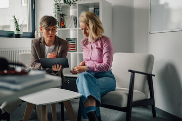 Two businesswomen using digital tablet during meeting in office