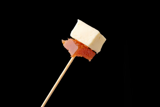 A delicious snack of creamy cheese topped with a slice of quince paste, elegantly presented on a dark slate board, perfect for gourmet finger food presentations.