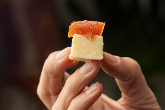 A delicious snack of creamy cheese topped with a slice of quince paste, elegantly presented on a dark slate board, perfect for gourmet finger food presentations.