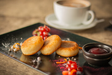 Golden syrniki (cheese pancakes) served with red currants, powdered sugar