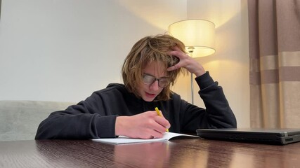 Teenager feeling frustrated while completing homework or taking an exam at home, facing challenges and stress