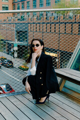 A stylish woman wearing sunglasses posing in a fashionable urban setting
