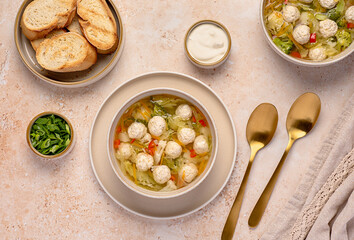 Food photography of soup with chicken meatballs and  vegetables, carrots, cabbage, broccoli, potatoes, bell pepper, broth, toasted bread, spring onion, sour cream