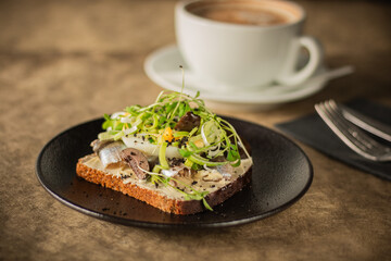 Close-up of a rustic toast topped with herring, boiled egg, greens