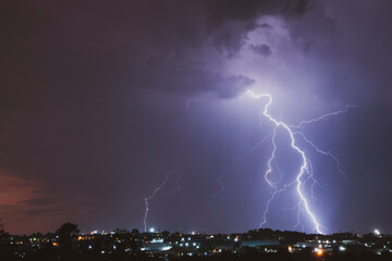 A stunning photograph of a lightning strike over a suburban area during a vibrant sunset, featuring...