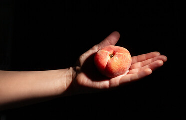 flat saturn peach in hand on black background