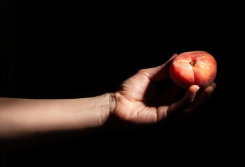 flat saturn peach in hand on black background