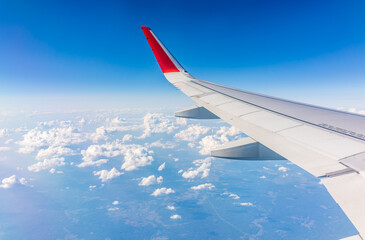 Fototapeta premium View from the airplane window at a beautiful cloudy sky and the airplane wing