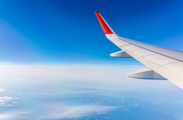 Fototapeta premium View from the airplane window at a beautiful cloudy sky and the airplane wing
