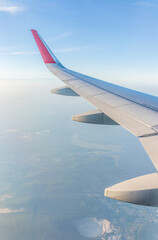 Fototapeta premium View from the airplane window at a beautiful cloudy sky and the airplane wing