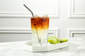 Refreshing espresso tonic drink and lime on white marble table