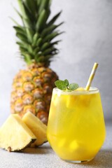 Tasty pineapple cocktail with mint in glass on gray table