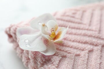 Orchid flower and towel on white marble table, closeup