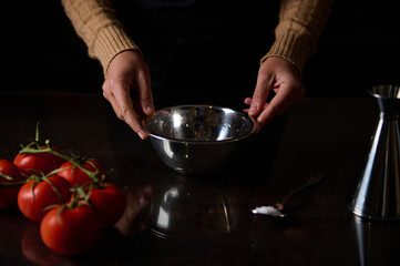 Preparing fresh tomatoes in a kitchen with stainless steel bowl