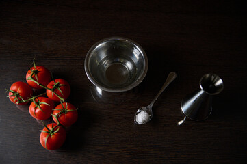 Fresh tomatoes with salt and bowl on dark wooden surface