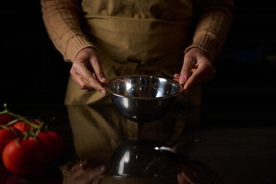 Hands holding a mixing bowl with fresh tomatoes on the counter - Powered by Adobe