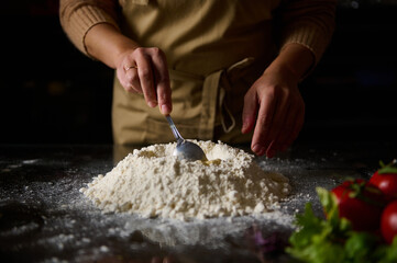 Chef preparing dough with fresh ingredients in kitchen setting