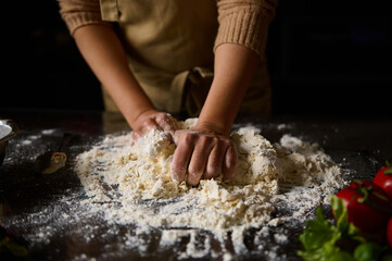 Baker kneading dough in a kitchen surrounded by fresh ingredients