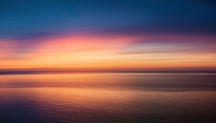 Obraz premium Serene Sunset Reflection: The sky ablaze with hues of fiery orange, pink, and blue, mirroring in the calm, still waters below. This breathtaking panorama evokes a sense of tranquility and peace. 