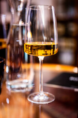 A close-up shot of a table with a modern wine glass filled with white wine, capturing the elegance of the glass and the refined atmosphere of the setting