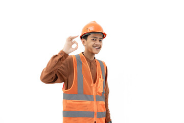 Young Indonesian male construction worker in full safety gear doing ok gesture while looking at camera, industrial and construction concept, isolated on white background.