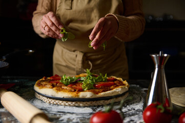 Woman preparing homemade pizza with fresh ingredients in cozy kitchen