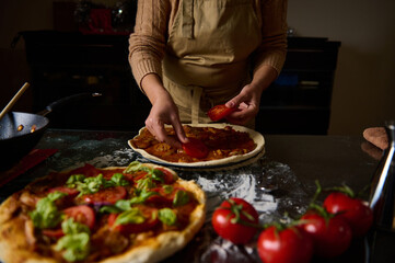 Person preparing homemade pizza with fresh ingredients in a cozy kitchen