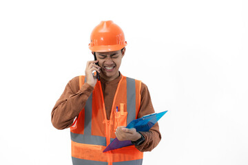 Young Indonesian male construction worker in full safety gear is on a voice call with his co-worker while holding a clipboard, construction and industry concept, isolated on white background.