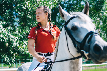 Obraz premium Hobbies with animal for recreating on nature environment, Caucasian female professional jockey enjoying leisure with beautiful stallion for practicing and riding on horseback during dressage