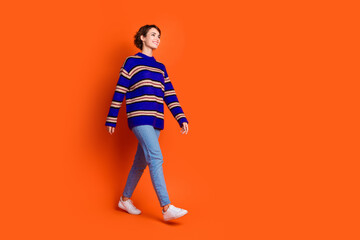 Photo of cheerful glad woman wear trendy clothes look empty space isolated on orange color background