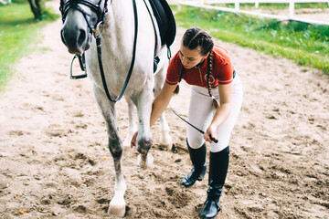 Professional Caucasian female jockey 20s practicing horseback training with horsewhip in paddock...