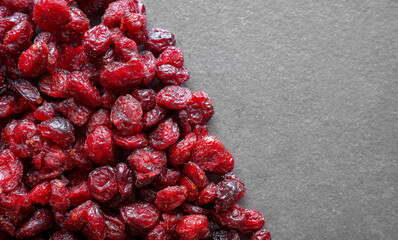 Close up photo of dried organic cranberries on a dark slate background, selective focus.