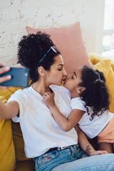 Obraz premium Mother kissing child during selfie
