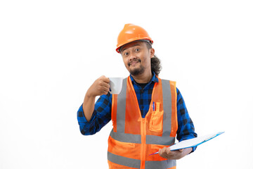 Indonesian male construction worker in full safety gear looking at report on clipboard while enjoying cup of coffee, construction and industry work concept, isolated on white background.