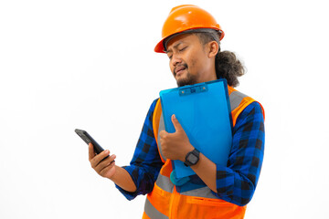 Indonesian male construction worker wearing safety gear looking very sad while looking at cellphone content while holding clipboard, construction and industry concept, isolated on white background.