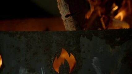 Large firewood burning in a rusty metal brazier, which depicts the symbol of fire. Slow motion. Close-up - Powered by Adobe