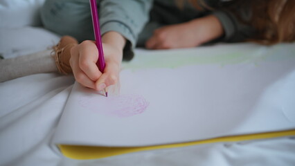 Naklejka premium Closeup child hand holding pencil drawing weekend. Unknown girl sitting mattress