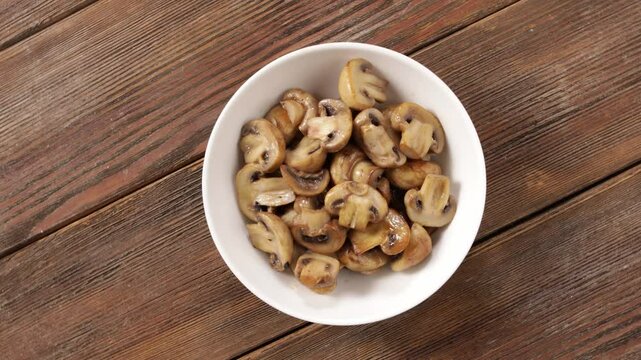 roasted mushrooms in bowl top view rotation on wooden surface