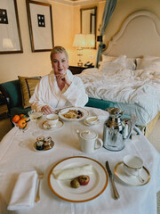 A woman enjoying a leisurely breakfast in a lavish hotel room