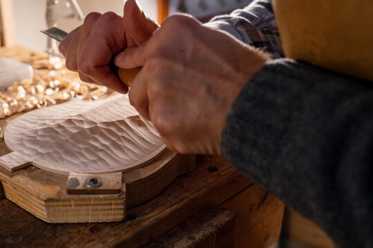 Luthier carving violin top plate with gouge and mallet