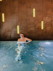 A man is relaxing in an elegant indoor pool at a luxurious resort