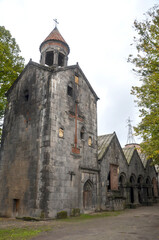 Naklejka premium An ancient stone Sanahin monastery stands amidst a lush green forest, showcasing historical architecture. Armenia