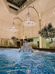 A man is relaxing in an elegant indoor pool at a luxurious resort