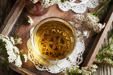 A cup of herbal tea with fresh yarrow or Achillea millefolium flowers